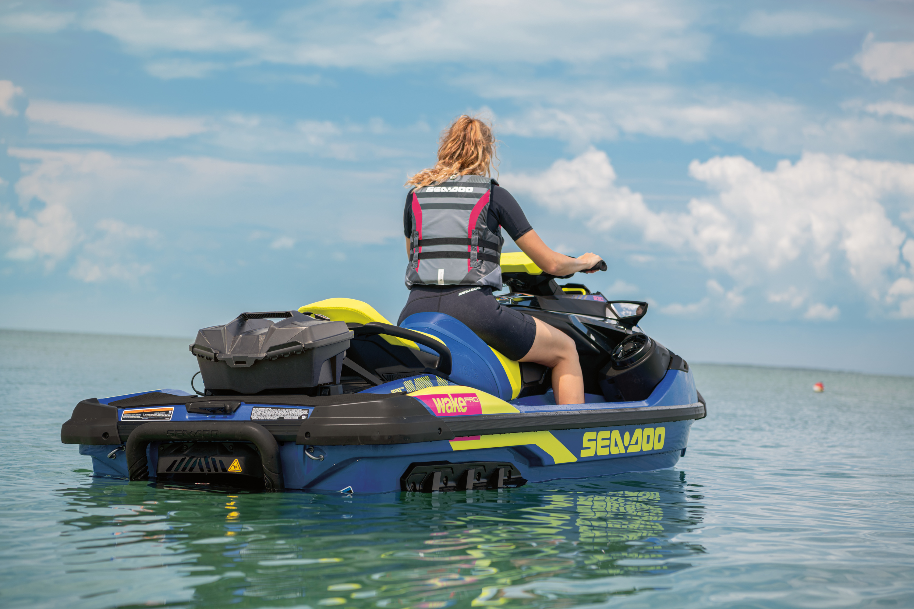 Woman on Sea Doo Wake Pro 230 in blue and yellow with cooler on the back